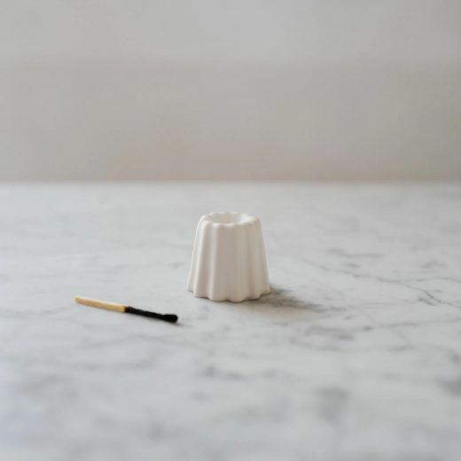 biały świecznik ovo z porcelany w kształcie ciastka canele na marmurowym blacie